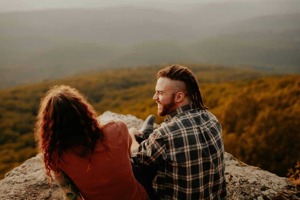Two friends sitting on a rock overlooking an autumn forest