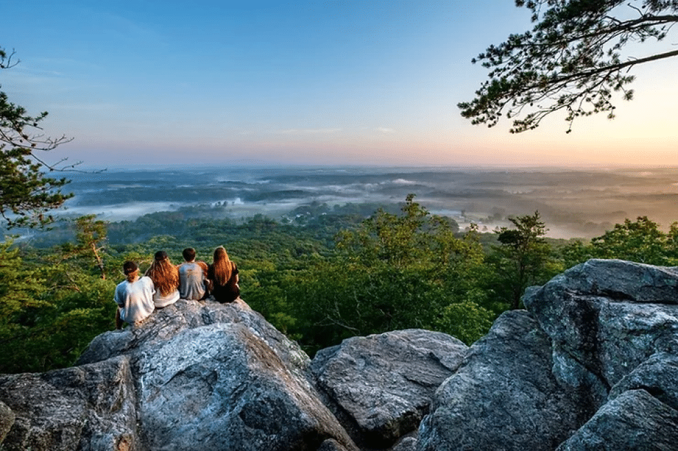 Group sitting on boulders above a misty valley at sunrise