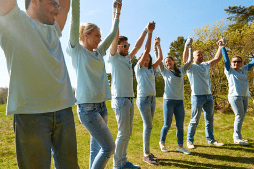 Team raising joined hands during an outdoor team-building activity