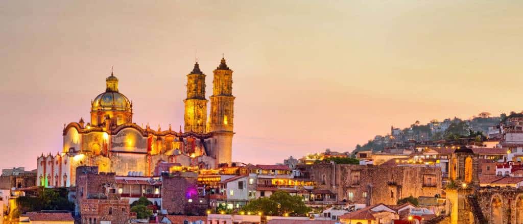 Colonial church towers lit at dusk in a Mexican hillside town