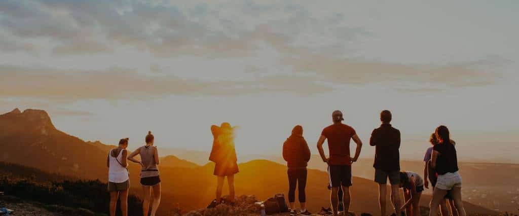 Group of hikers watching the sunset from a ridge