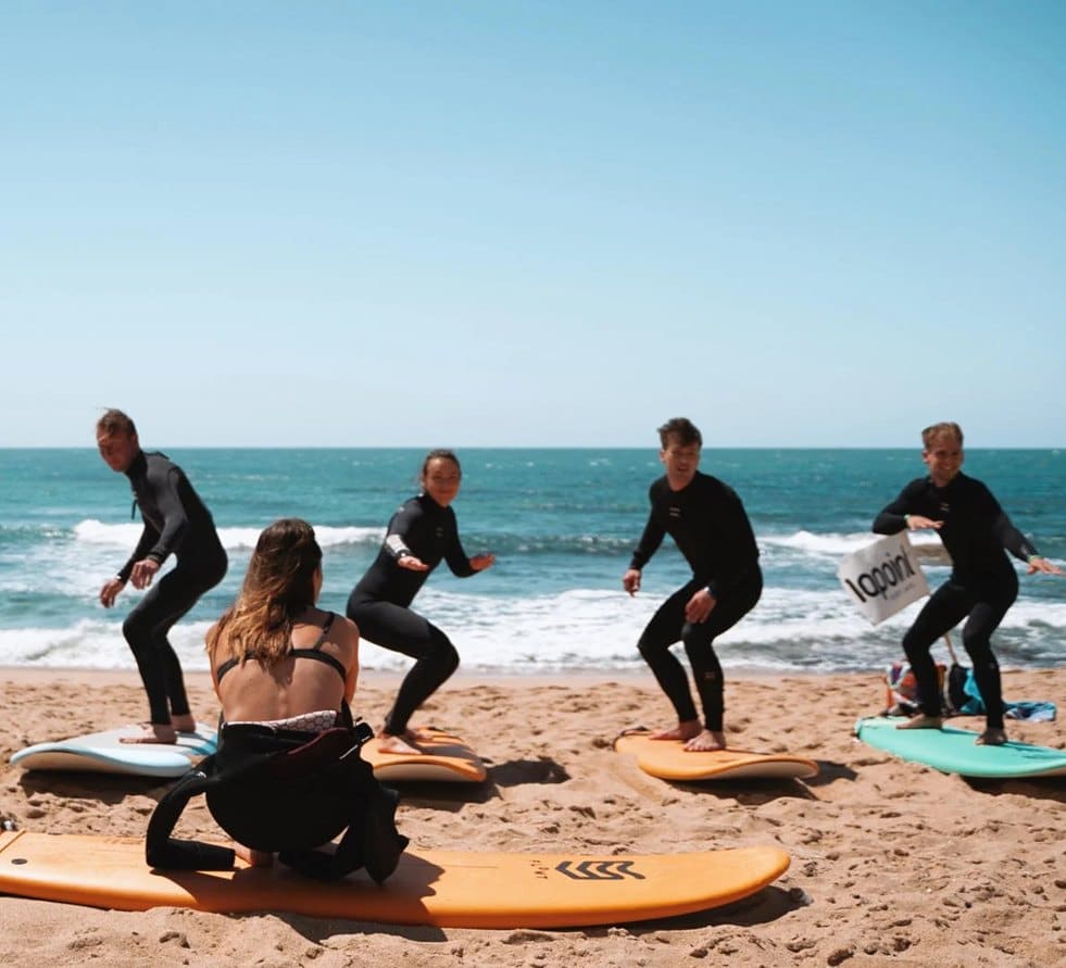 Instructor coaching a group surf lesson on the beach