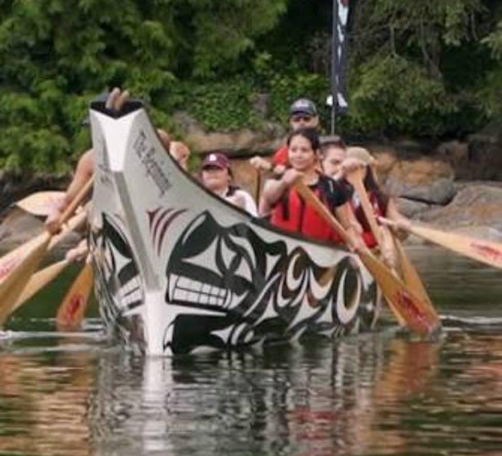 Team paddling a carved and painted cedar canoe near Vancouver