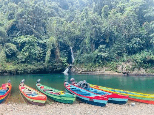 Longboats on the Navua River below a rainforest waterfall in Fiji