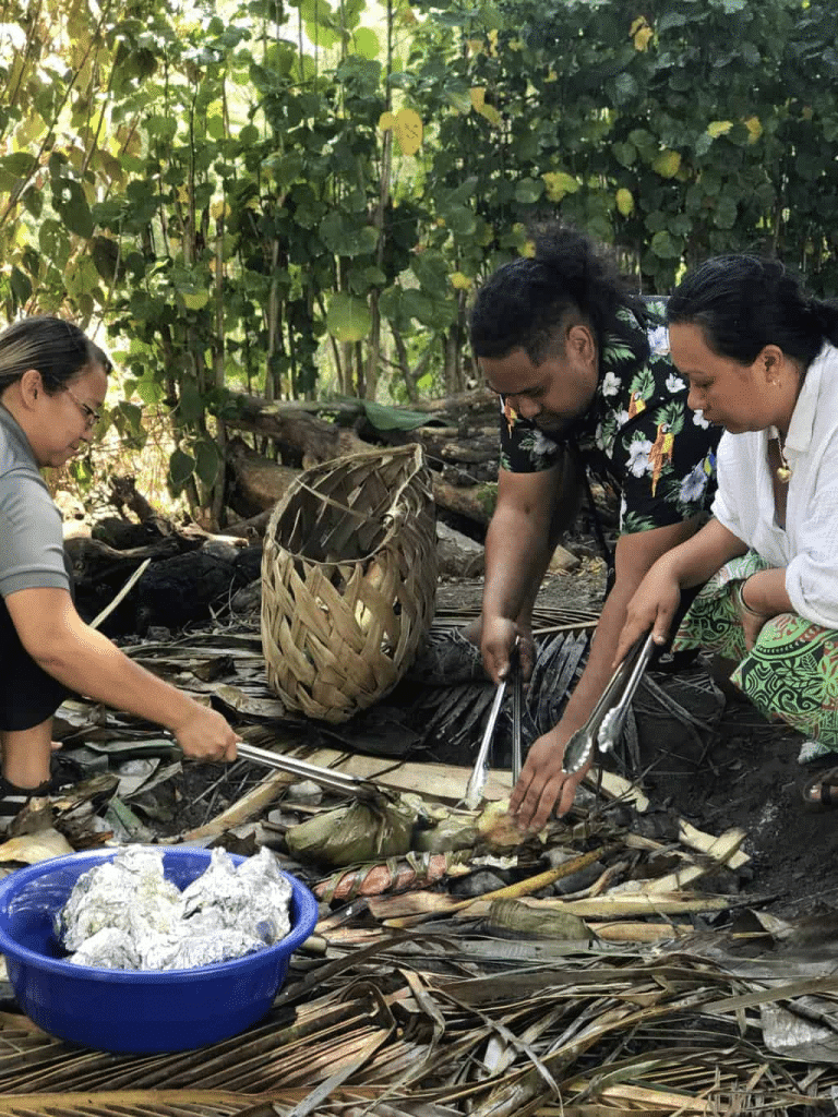 Village hosts lifting food from a traditional lovo earth oven in Fiji