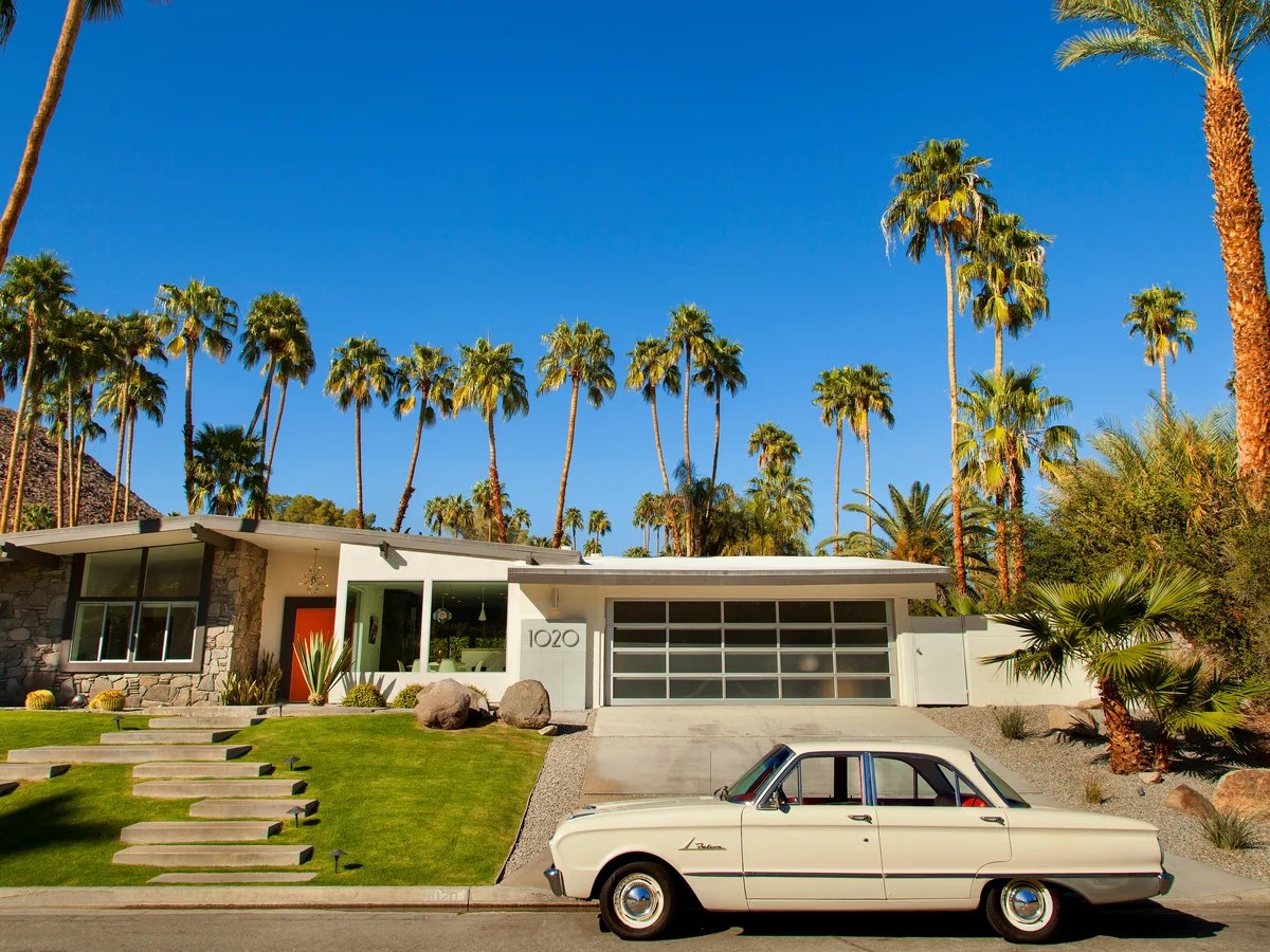 Midcentury modern home with a vintage car and palm trees in Palm Springs