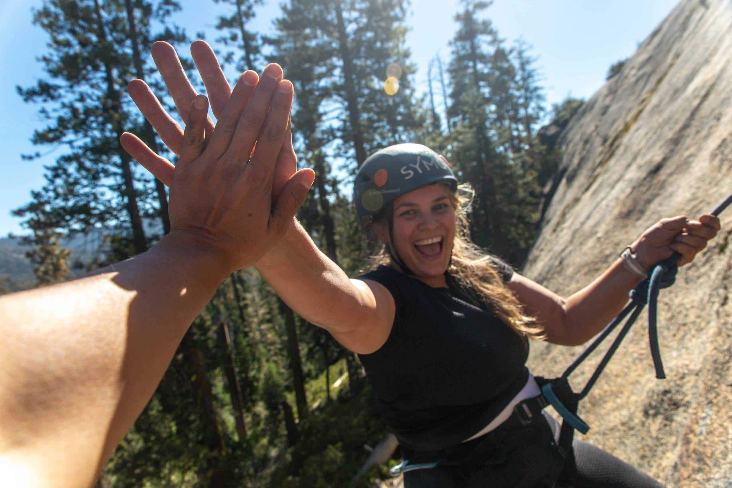 Climber high-fiving a teammate on a granite wall in Yosemite