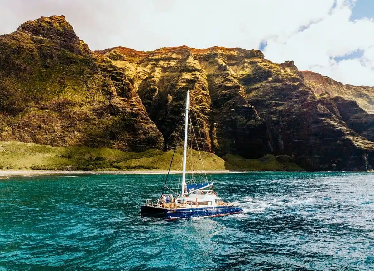 A catamaran sailing beneath the cliffs of the Na Pali Coast, Kauai