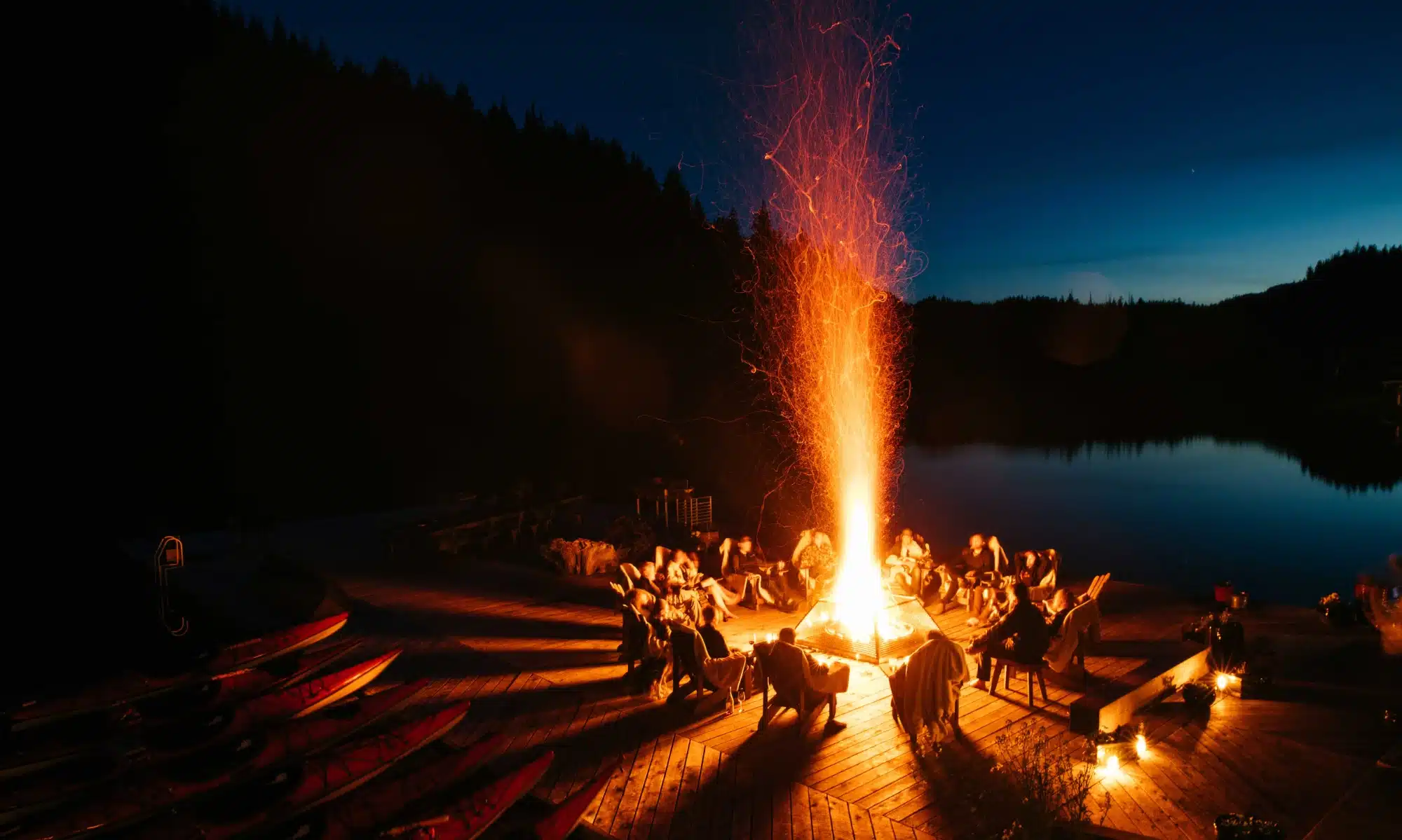 A retreat group around a lakeside fire pit at dusk