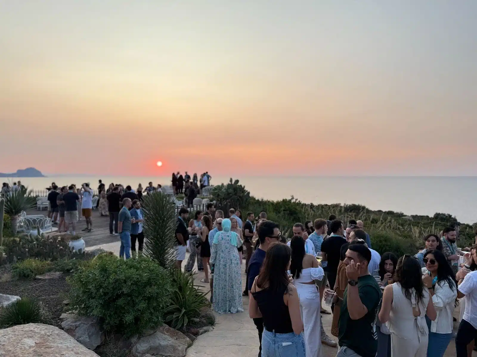 A retreat group gathered on a seaside terrace at sunset